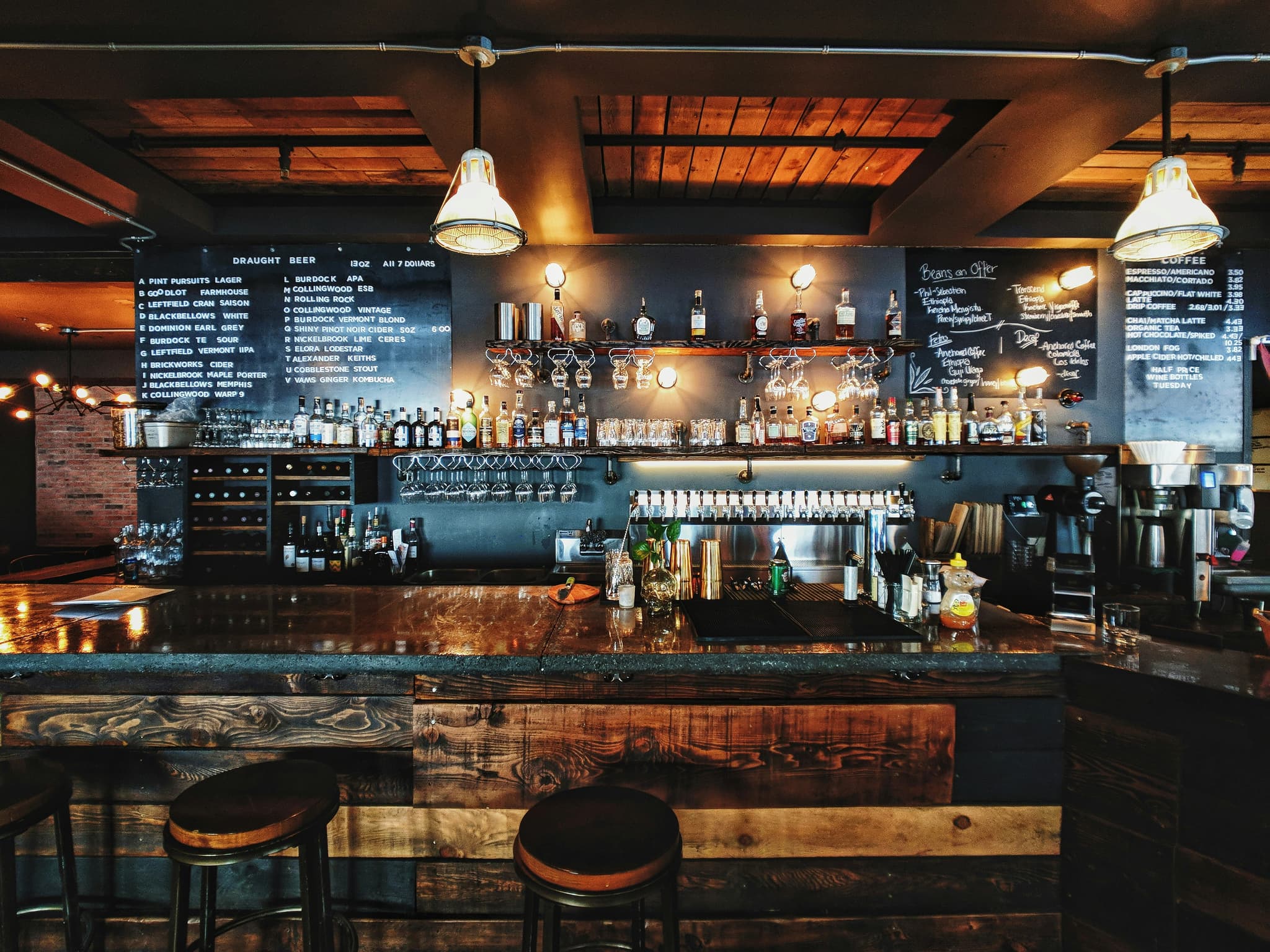 Rustikale Bar mit dunklem Holz, Kreidetafel und Zapfanlage — Gastronomie die ihre Reservierung über das Tavolo-WordPress-Plugin annimmt.