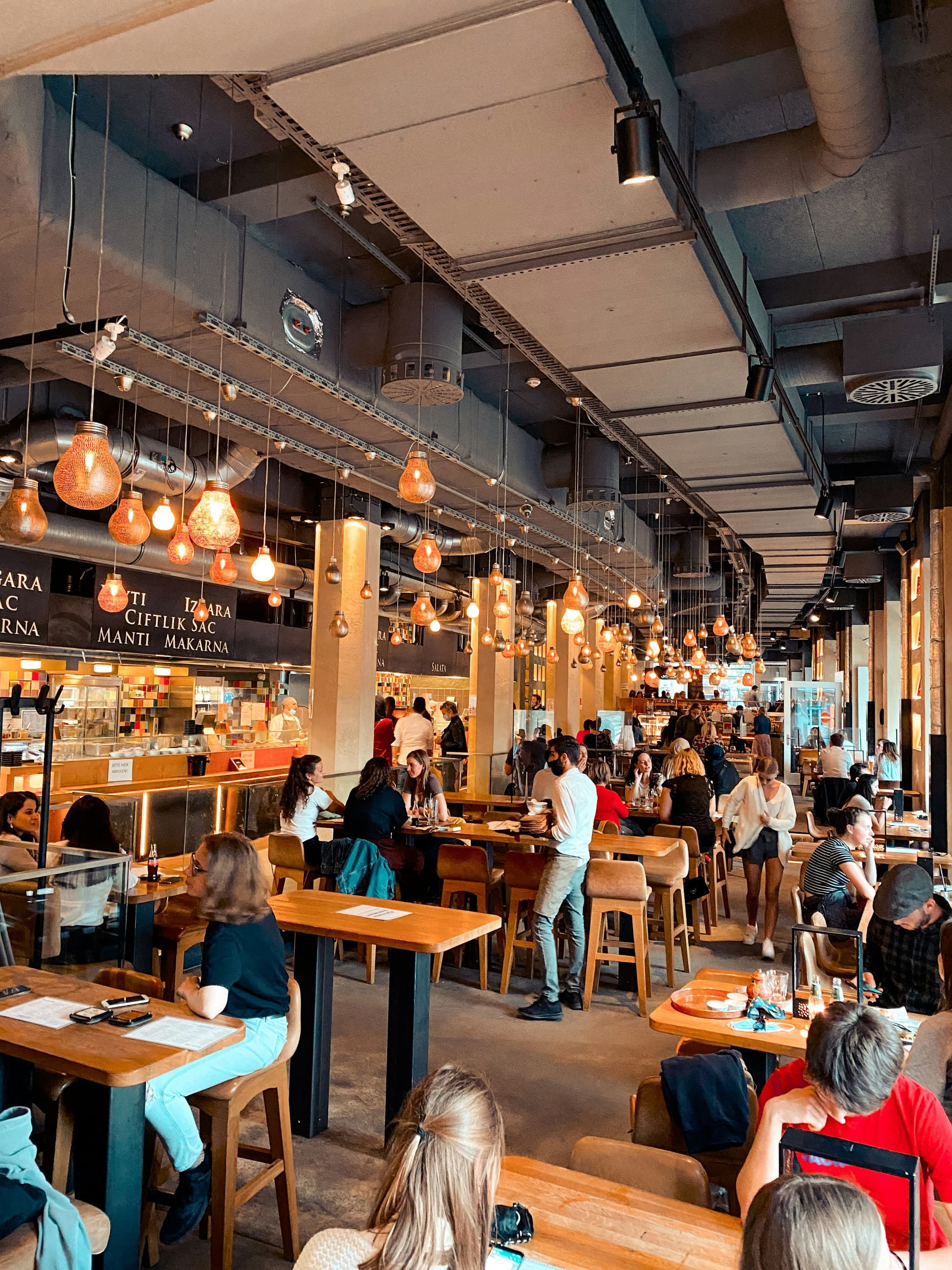 Belebtes Markt-Restaurant mit Edison-Beleuchtung — voller Tag im Restaurant, sauber organisiert über die Auslastungs-Matrix.