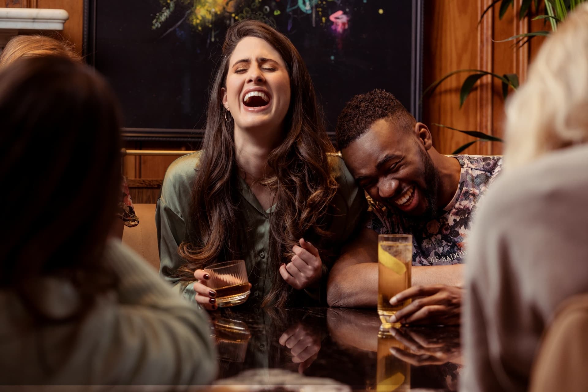 Freunde lachen gemeinsam beim Abendessen am Restauranttisch, zufriedene Gäste die nach dem Besuch automatisch um eine Google-Bewertung gebeten werden.