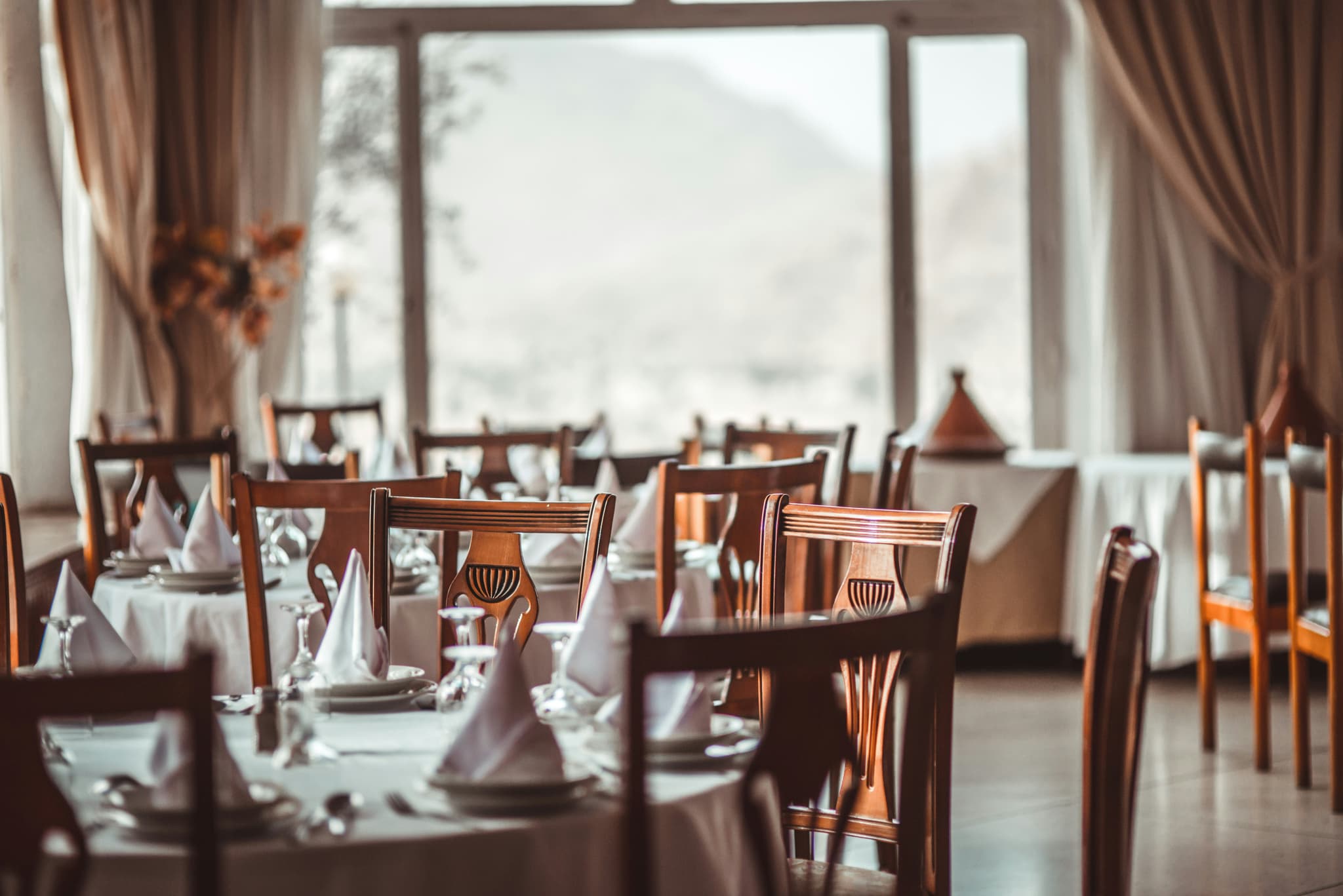Eleganter Restaurant-Saal mit weißen Tischdecken und Bergblick — klassisches Premium-Restaurant das mit Tavolo monatlich vierstellige Cover-Fees spart.