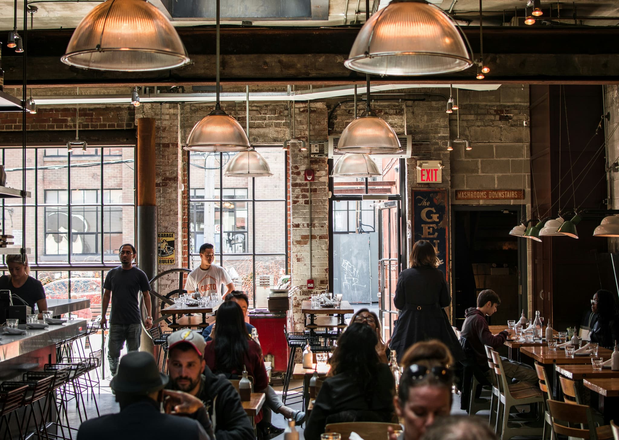 Belebtes Restaurant mit Industrial-Style und voller Lunch-Atmosphäre — Gastronomie die mit Tavolos Auslastungs-Matrix den Überblick über alle Tische und Slots behält.