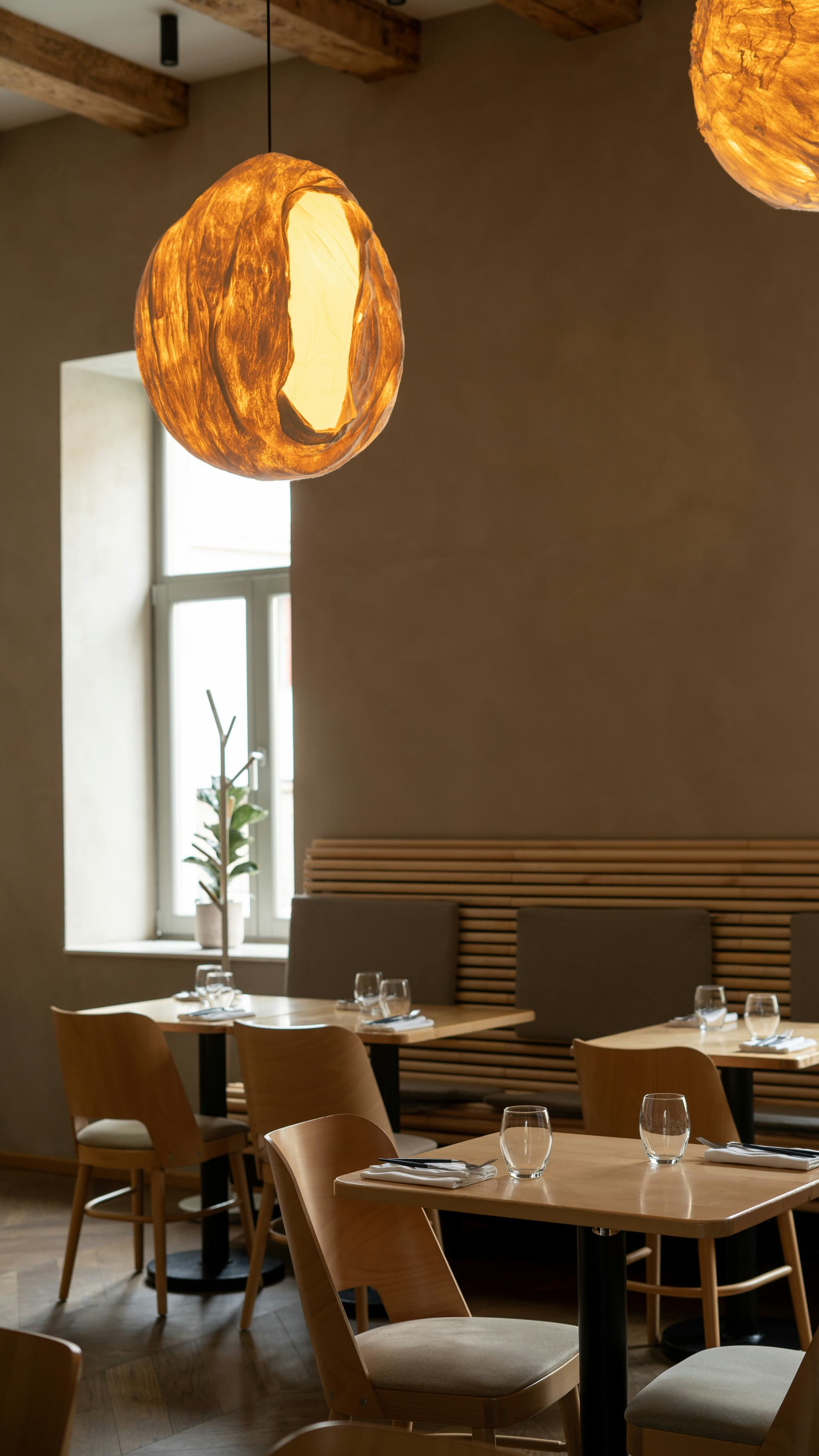 Warmes Restaurant-Interior mit organischer Hängelampe und Holz-Naturmaterialien — Gastronomie die ihren Gästen mit DSGVO-konformer Datenverarbeitung Vertrauen vermittelt.