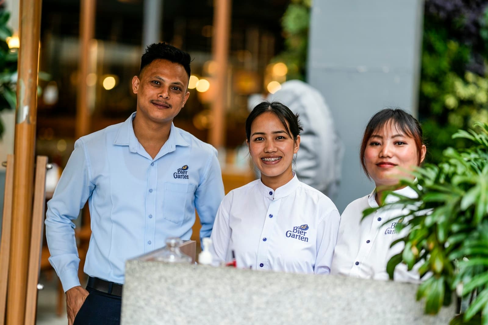 Lächelndes Restaurant-Team hinter der Theke — Gastronomie, die mit Tavolo alle Funktionen für Reservierung und Auslastung nutzt.